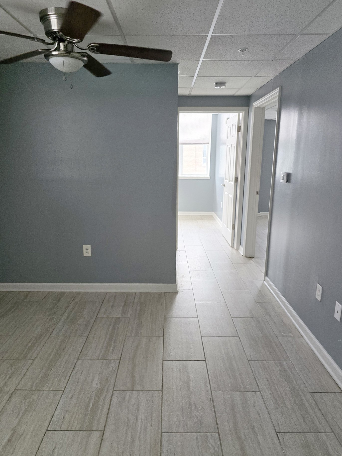 A room with a ceiling fan and tile flooring.